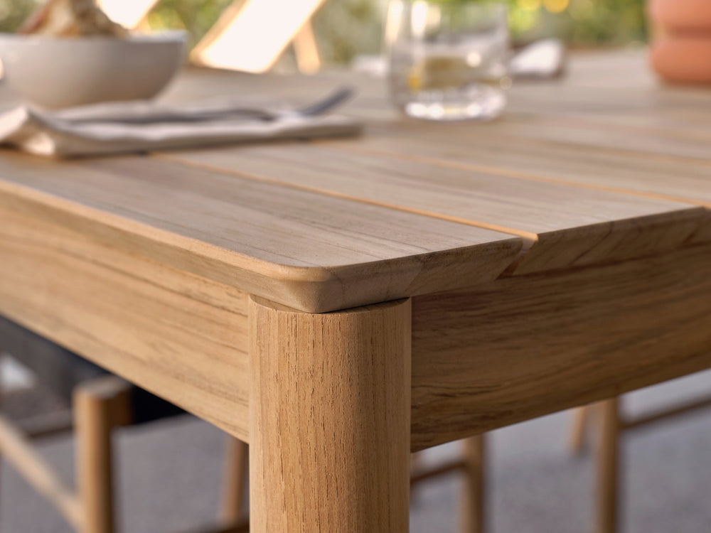 A low angle detail shot of a Neighbor teak outdoor dining table