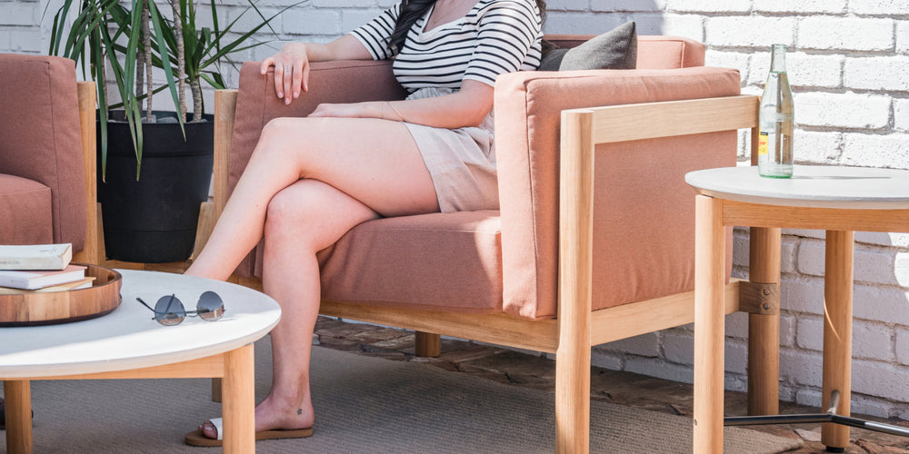 A woman relaxing in her Neighbor teak outdoor lounge chair