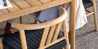 A detail shot of a Neighbor teak outdoor dining chair as part of a dining set