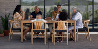 A family enjoying a meal around their Neighbor teak outdoor dining set