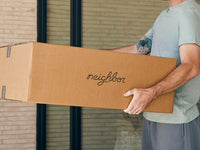 A person carrying a Neighbor teak outdoor furniture frame box