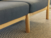 A detail shot of a Neighbor braid rug in pepper nestled beneath a sofa leg