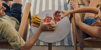 A couple sharing drinks on their patio set over a Neighbor outdoor concrete side table