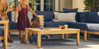Two children playing with cars on their Neighbor teak outdoor coffee table